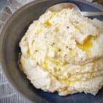 mashed cauliflower in a grey pasta bowl drizzled with melted butter