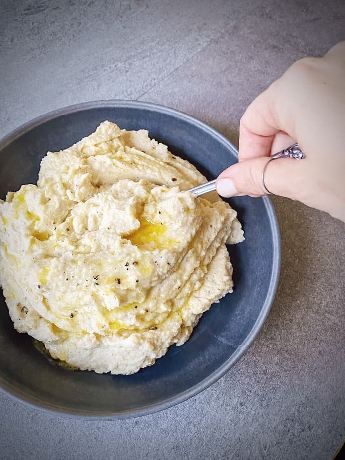 hand grabbing a serving spoonful of cauliflower mashed potatoes