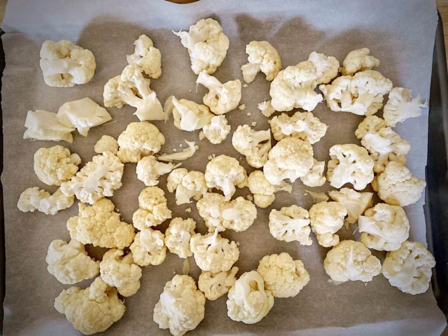 raw cauliflower florets on a parchment-lined sheet pan.