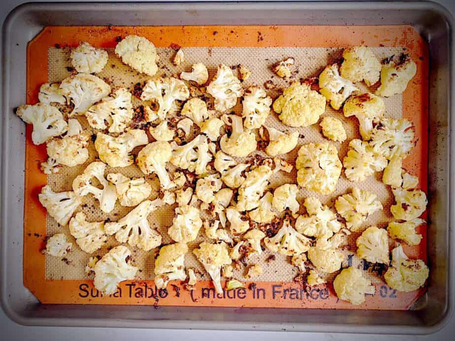 garlic roasted cauliflower florets on the sheet pan after first roast.