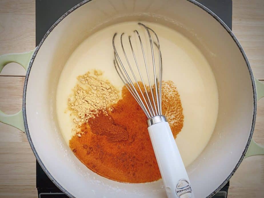 paprika and mustard powder added to creamy soup base in dutch oven with whisk