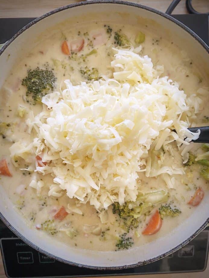 shredded white cheddar piled atop broccoli soup for final step of recipe