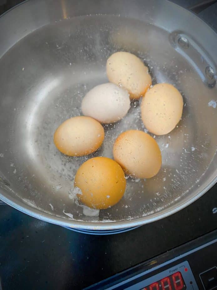 6 brown eggs simmering in silver saucepan