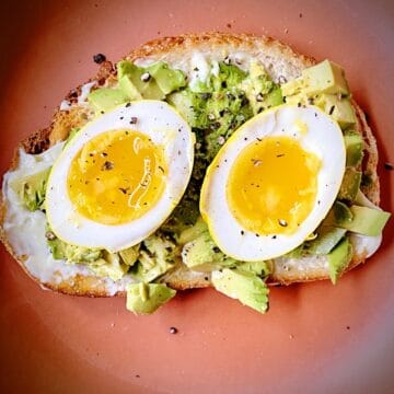 overhead close up shot of halved turmeric pickled egg on avocado toast.