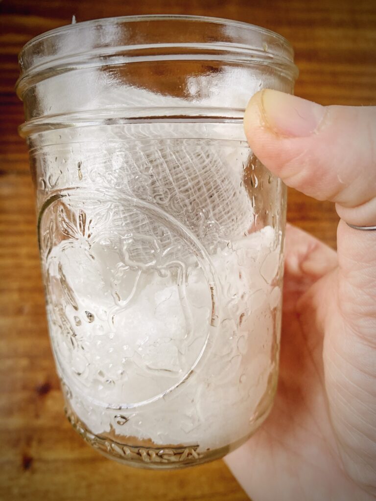 decarbed flower in a cheesecloth packet in a mason jar with coconut oil