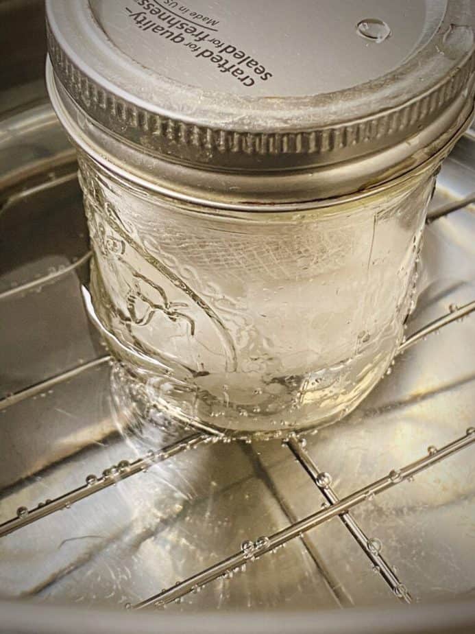 mason jar with coconut oil, sachet of decarbed CBD flower with lid on in the insert of instant pot with water