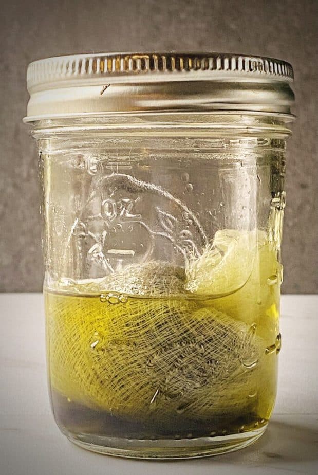 sachet of decarbed cbd flower steeping in coconut oil in a small mason jar