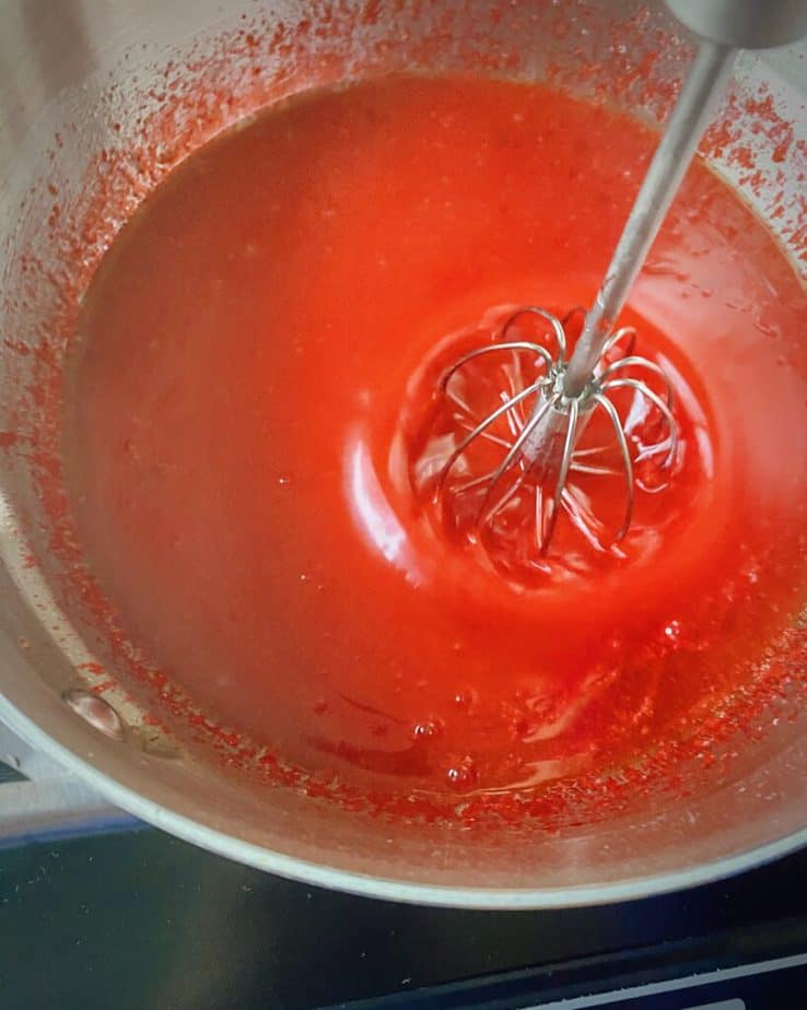 overhead shot of homemade cbd gummies mixture being whisked in a saucepan over the heat