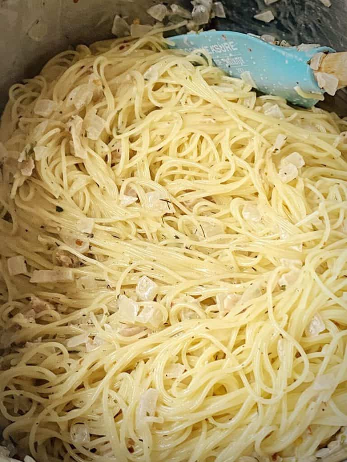 close up of linguini and clams after being stirred together in pan and adding pasta water