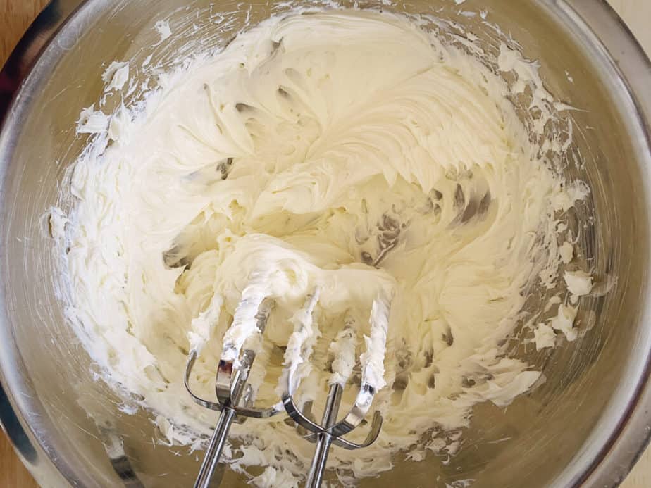 cream cheese in a silver mixing bowl after being beaten to a creamy state