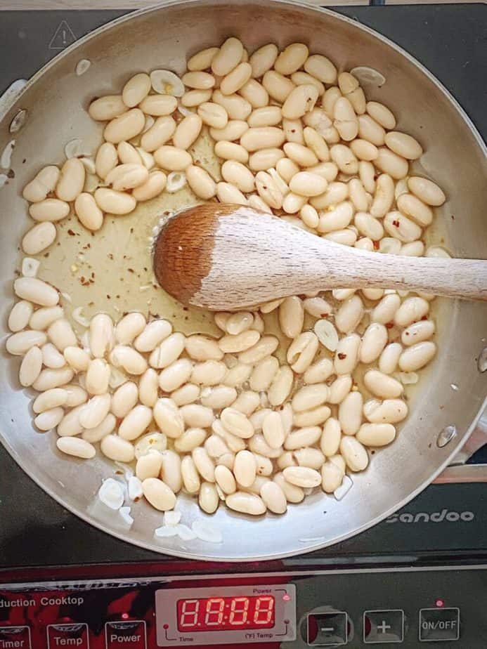 beans added to white wine mixture with a wooden spoon