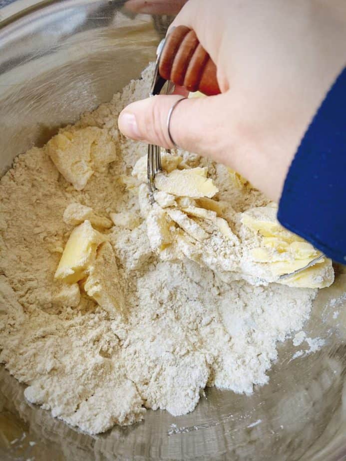 hand using a pastry cutter to cut butter into pancake mix cobbler dough