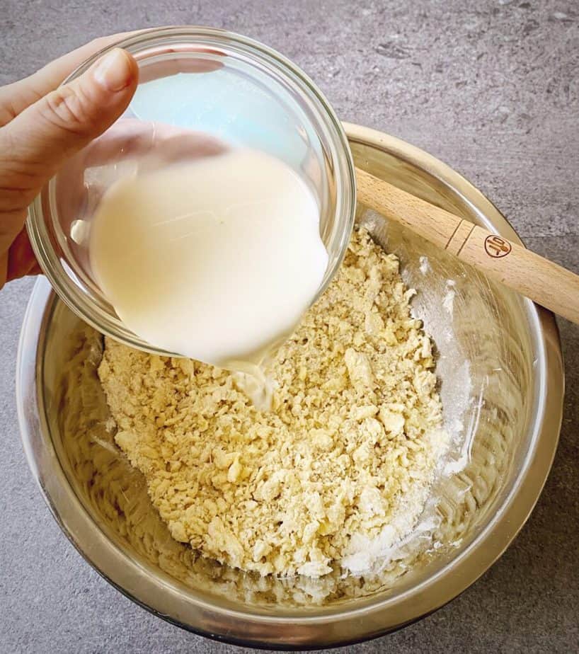 hand pouring milk into butter and dry cobbler mix