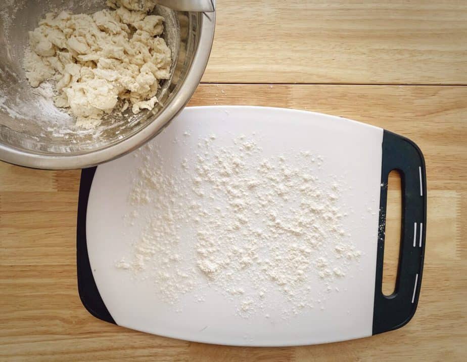 bowl of biscuit dough next to a cutting board sprinkled with flour