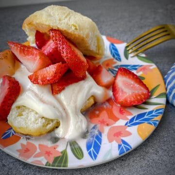 plated strawberry shortcakes on a floral dessert plate with a gold fork.