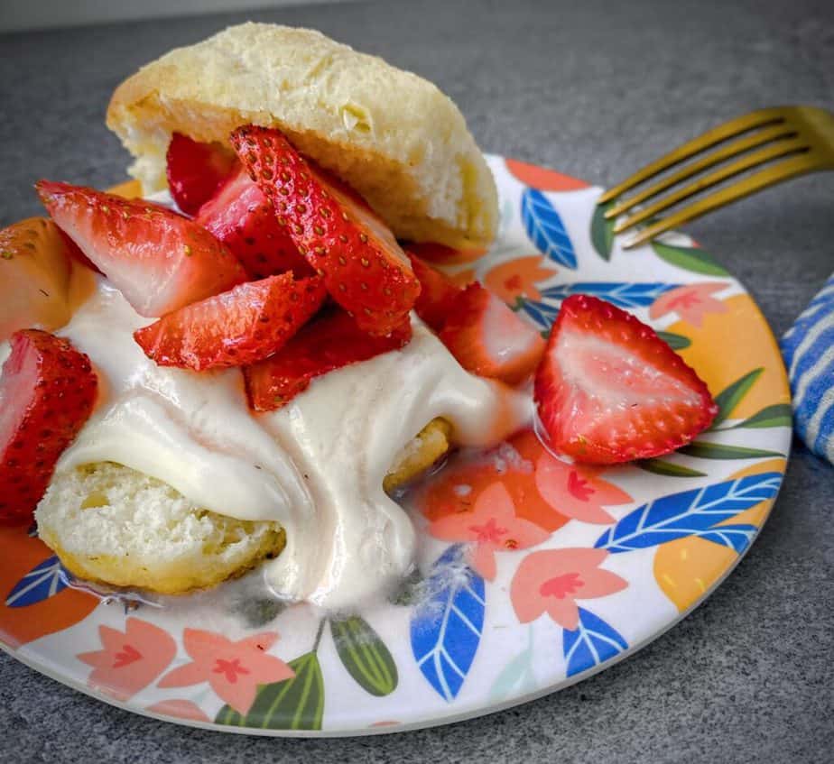 45 degree angle shot of classic strawberry shortcakes on a biscuit, showing the macerating juices running through the whipped cream