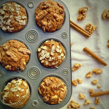 overhead shot of 5 muffins with a cup filled with walnuts.