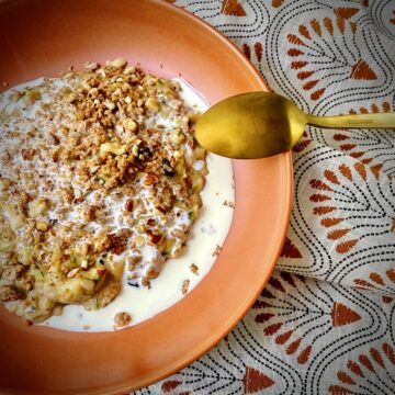 overhead shot of zucchini oats topped with cream and grain free granola.