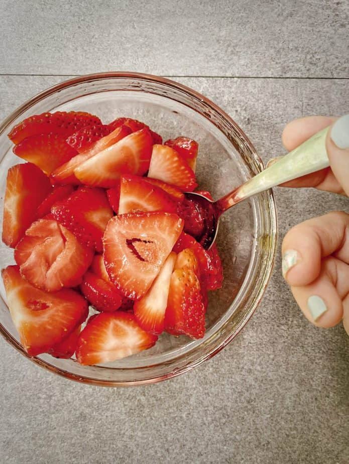 hand stirring strawberries with honey to get juicy and macerated
