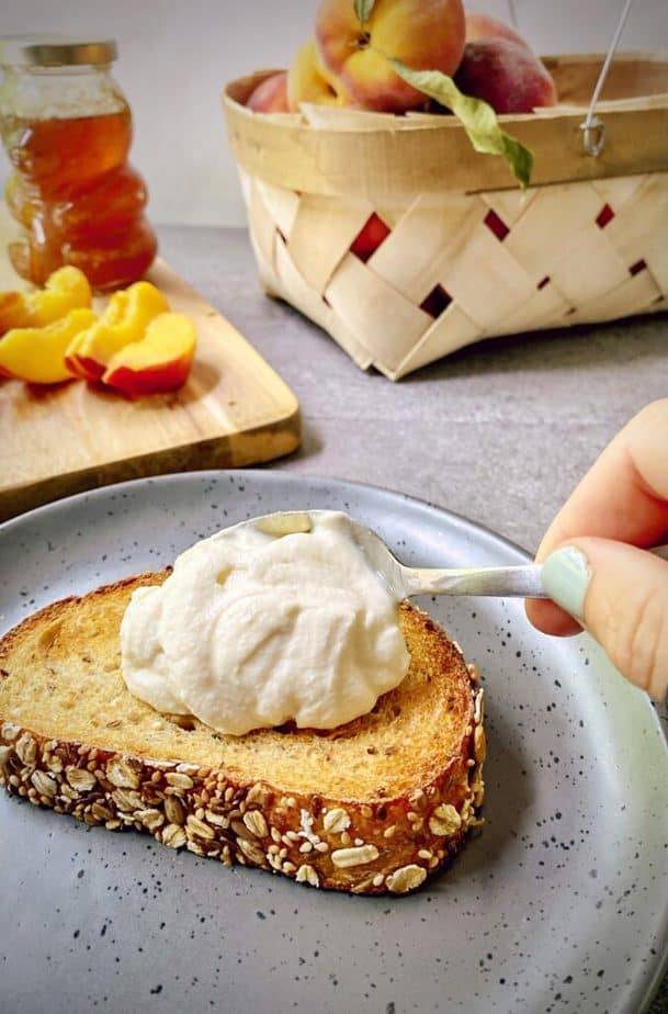 spoon adding a swoosh of sweetened ricotta to the toast