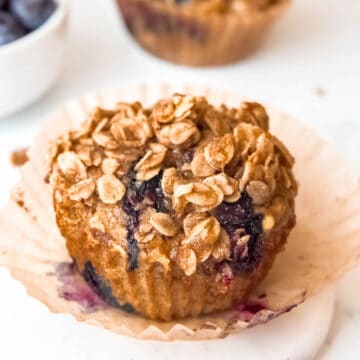 square hero image of a banana blueberry oatmeal muffin with cinnamon oat streusel topping.