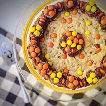 peanut butter chocolate chip cookie cake decorated with peanut butter chocolate buttercream and various reese's candies.