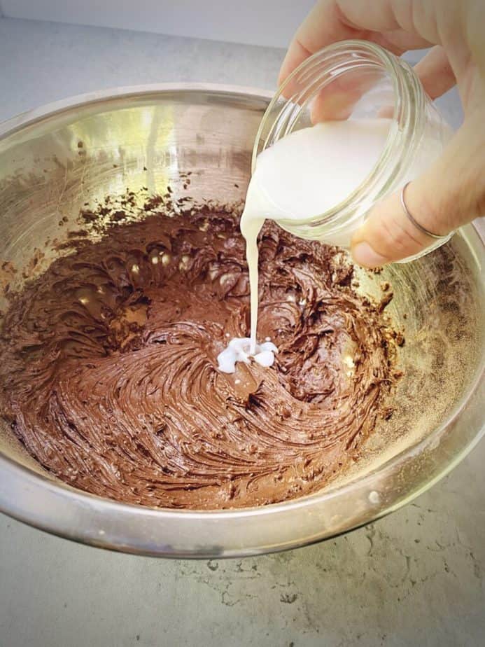 hand adding milk to frosting