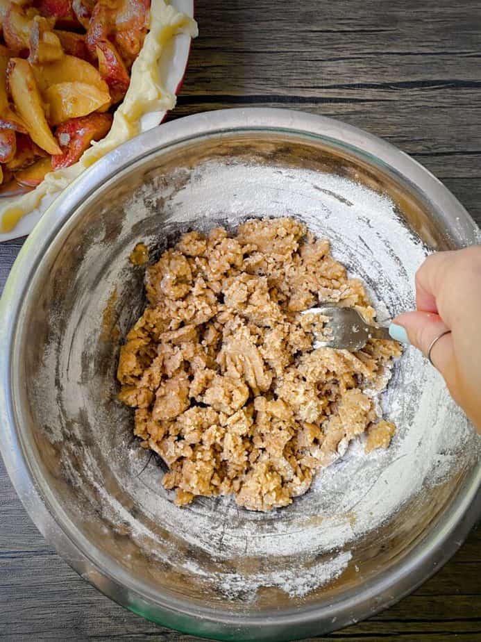 hand using a fork to stir the crumble mixture until uniform