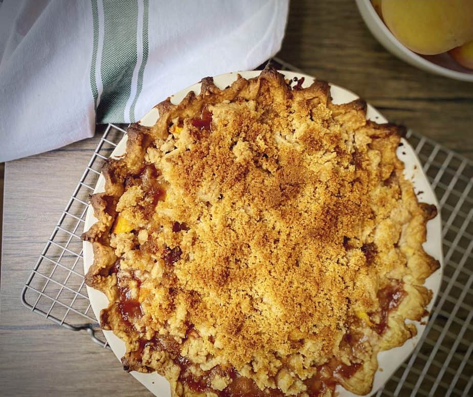 peach crumble pie in a red and white pie dish