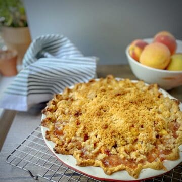 peach crumble pie in a red and white pie dish.