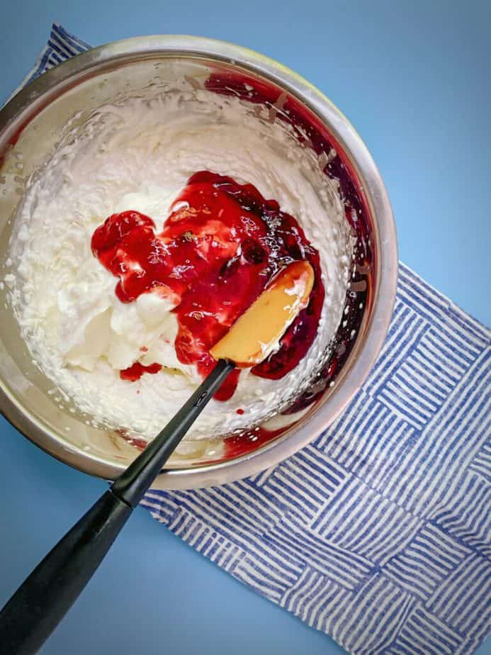 plain greek yogurt and berry preserves added to bowl with whipped cream mix