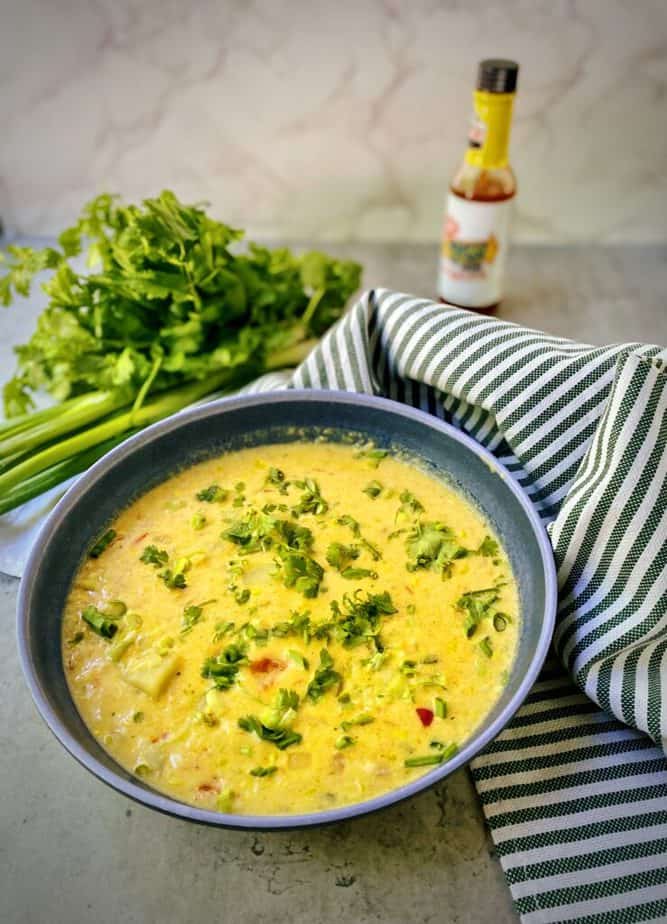 blue pasta bowl with easy corn chowder garnished with hot sauce, scallions and cilantro