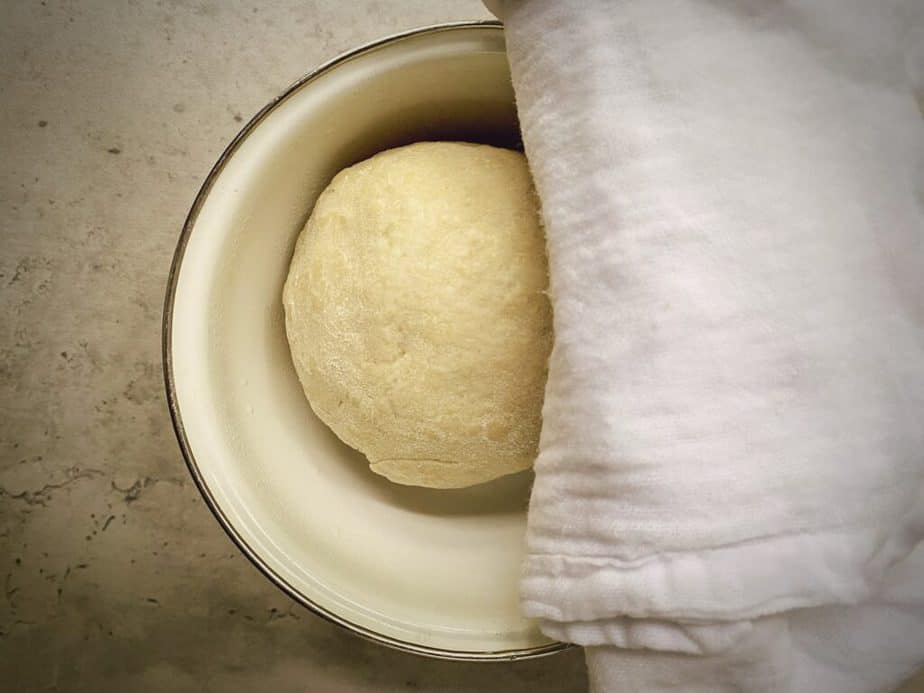 resting scallion pancake dough ball in an oiled bowl with a damp towel