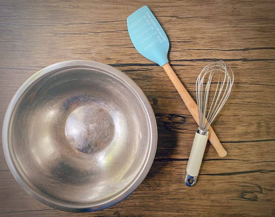 mixing bowl, whisk and spatula on a wooden table