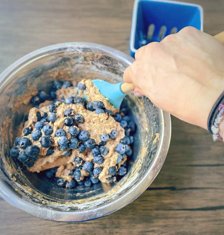 folding blueberries into muffin batter with a silicone spatula