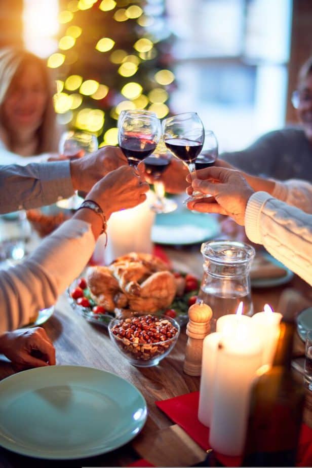 people cheers-ing with glasses of wine over a holiday meal.