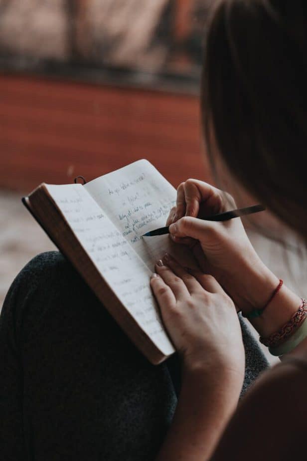 woman writing her holiday meal plan in a journal.