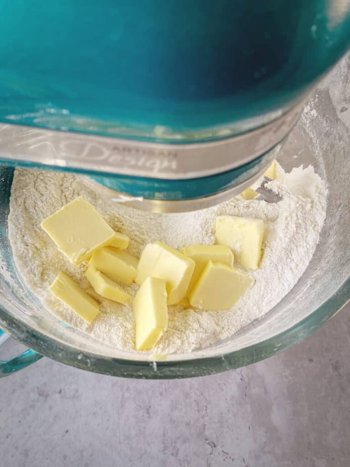 adding chunks of butter to bowl with dry ingredients.