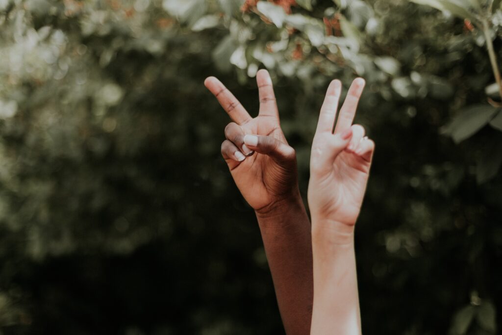 one Black hand and one white hand criss-crossing with the peace sign. 