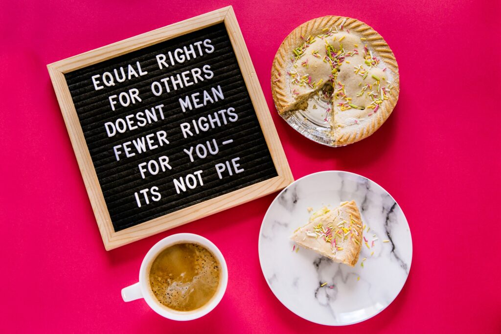 overhead shot of letterboard that reads "equal rights for others doesn't mean fewer rights for you — it's not pie" on a hot pink background with a pie. 