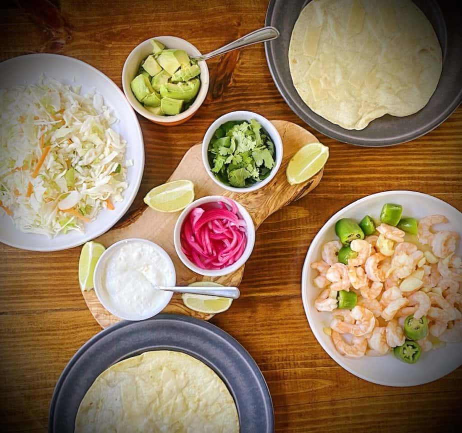 overhead shot of a shrimp taco spread with red onion pickles in the center.