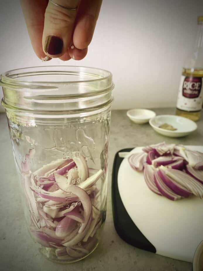 adding salt to first layer of red onions.