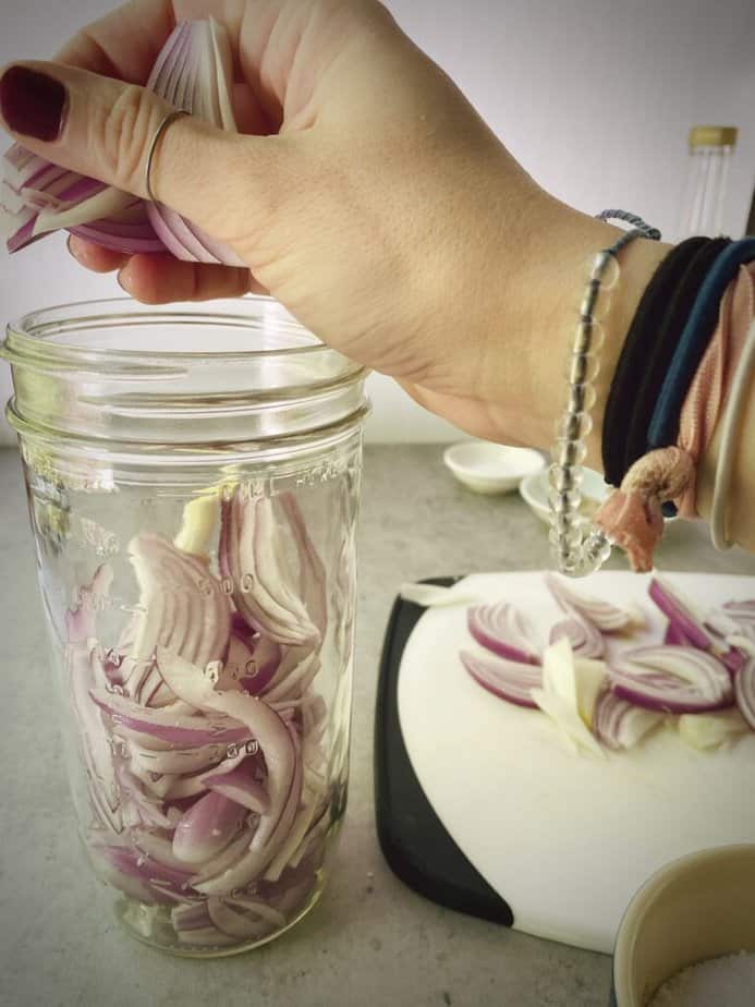 adding second layer of red onions to jar.