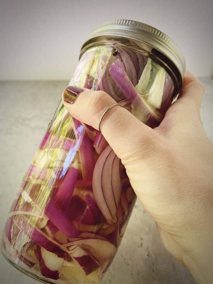 shaking container with red onions and vinegar for pickling.