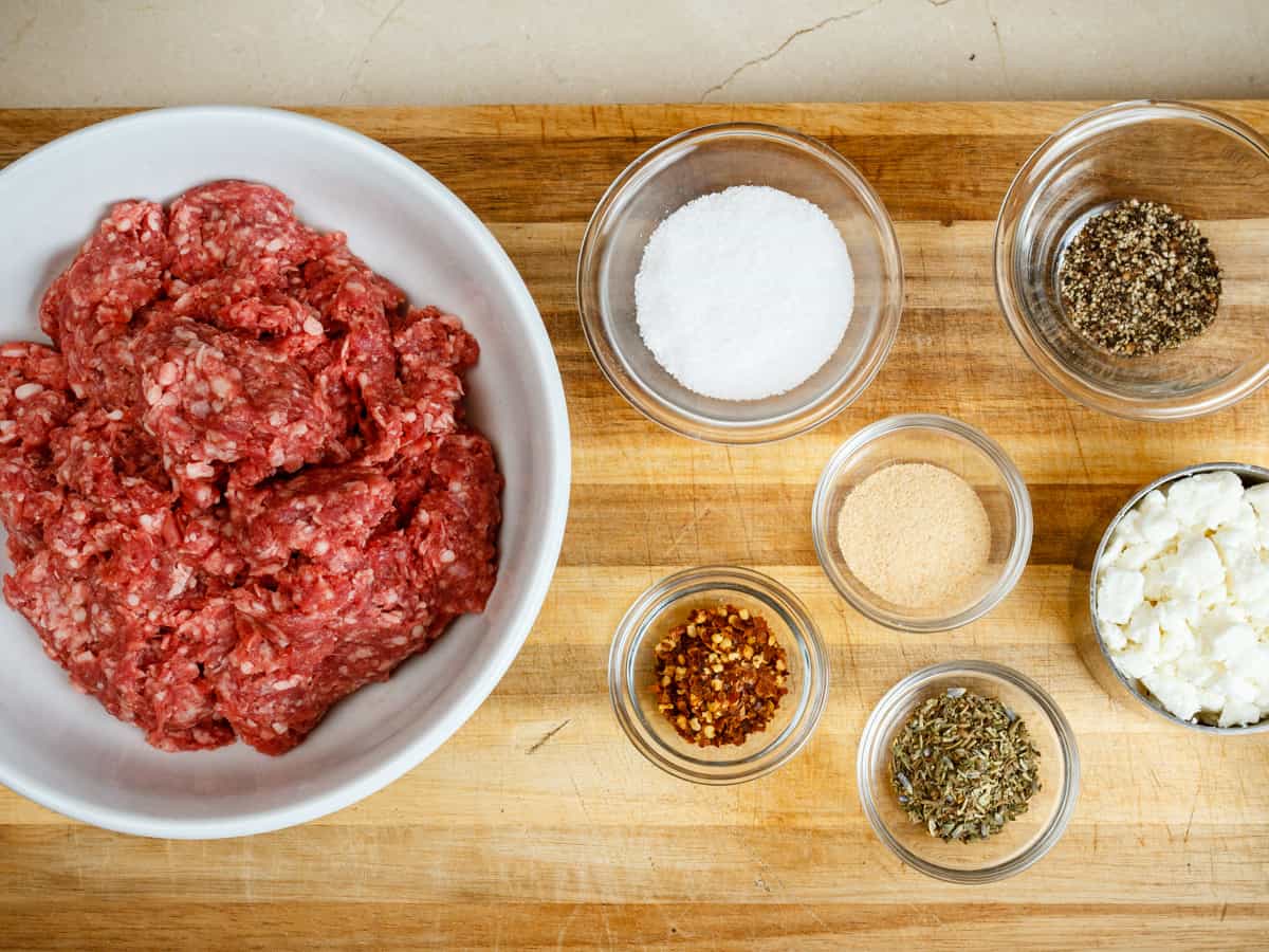 ingredients for making greek burger patties measured out in bowls.