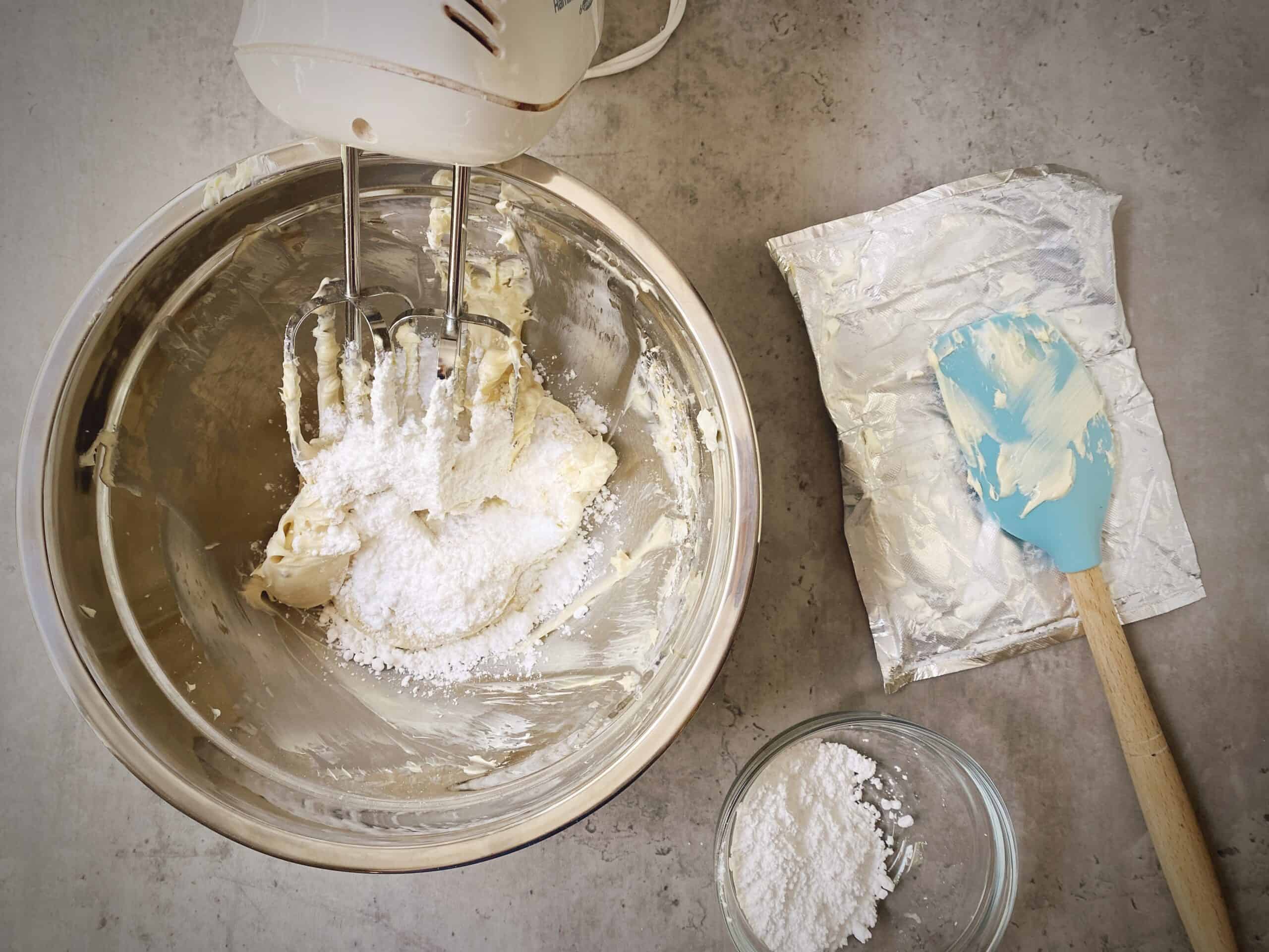 adding more powdered sugar to the cheesecake dip.