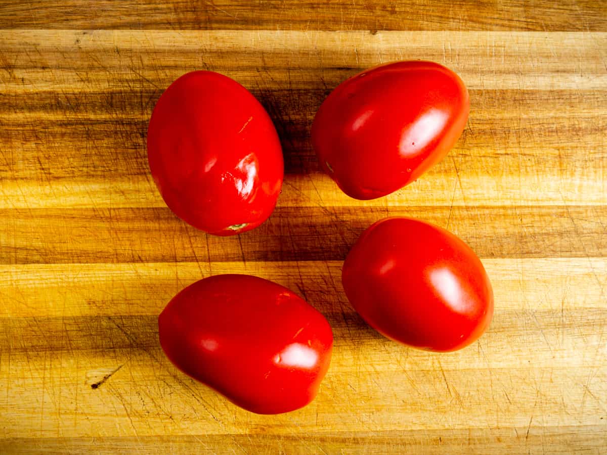 roma tomatoes on a chopping board.