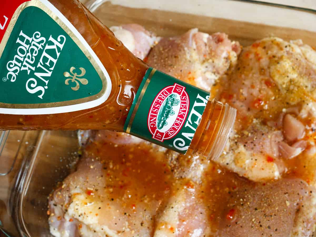pouring italian dressing over chicken thighs to marinate.