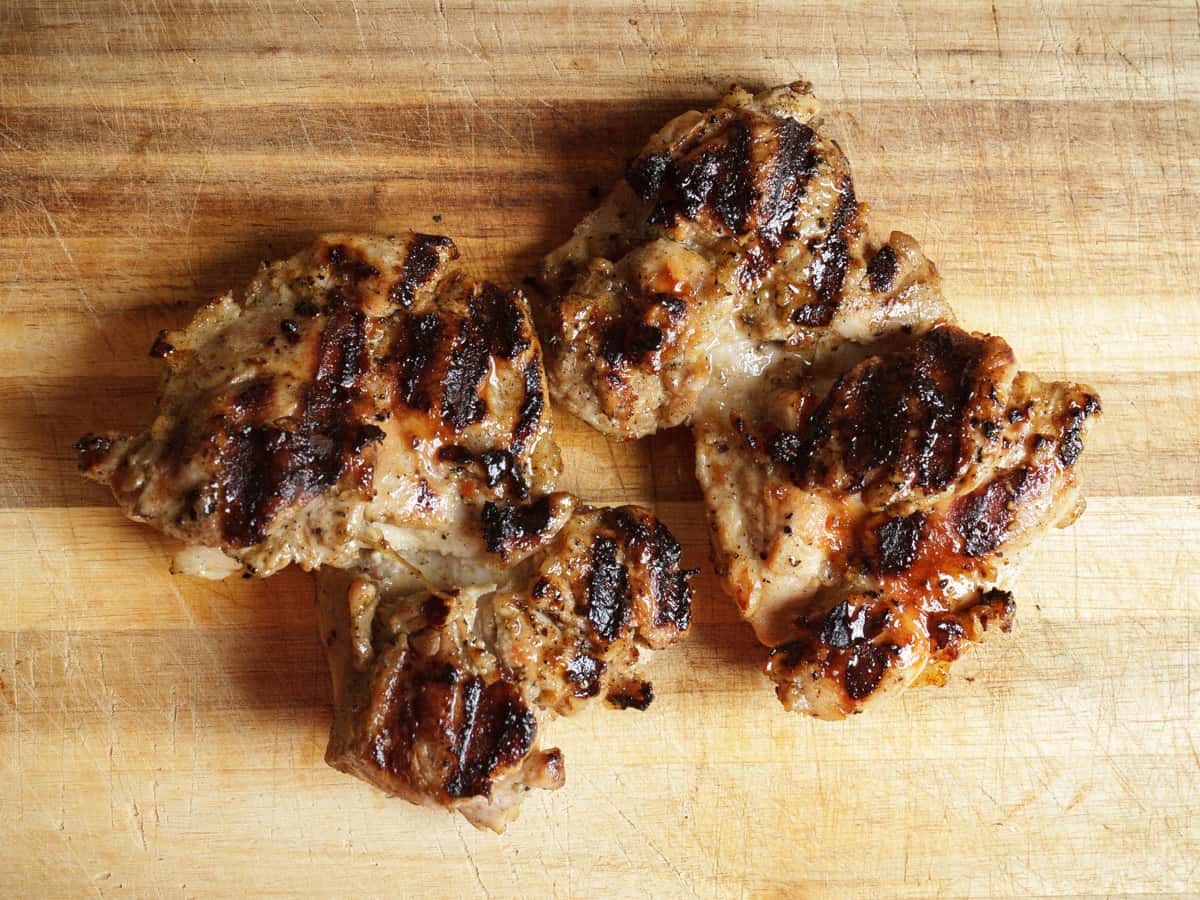 chargrilled chicken thighs on a cutting board.