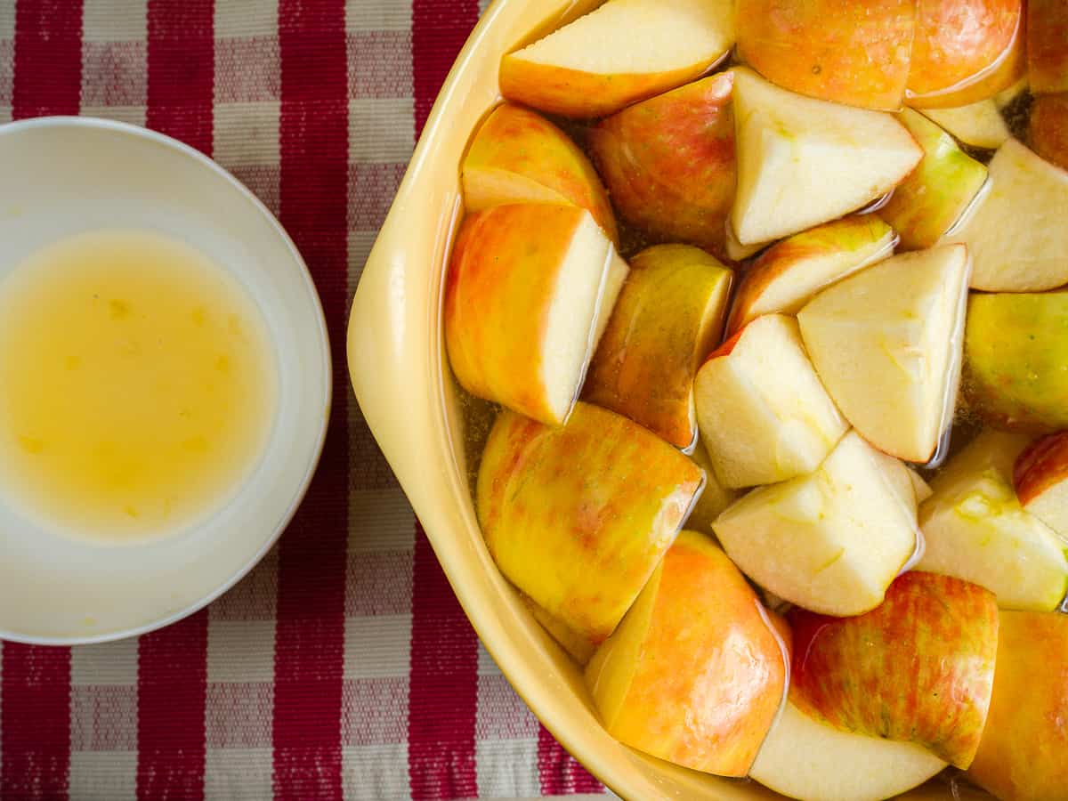 apples cut into cubes and soaking in lemon water with a small bowl of freshly squeezed orange juice to the side.